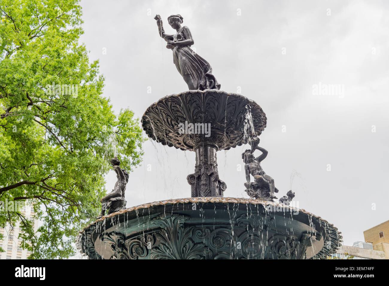 Memphis, Tennessee, 24 MAGGIO 2026 – Vista ad angolo basso di una fontana decorativa in bronzo con una statua femminile centrale e acqua che scorre nella vasca, posizionata Foto Stock
