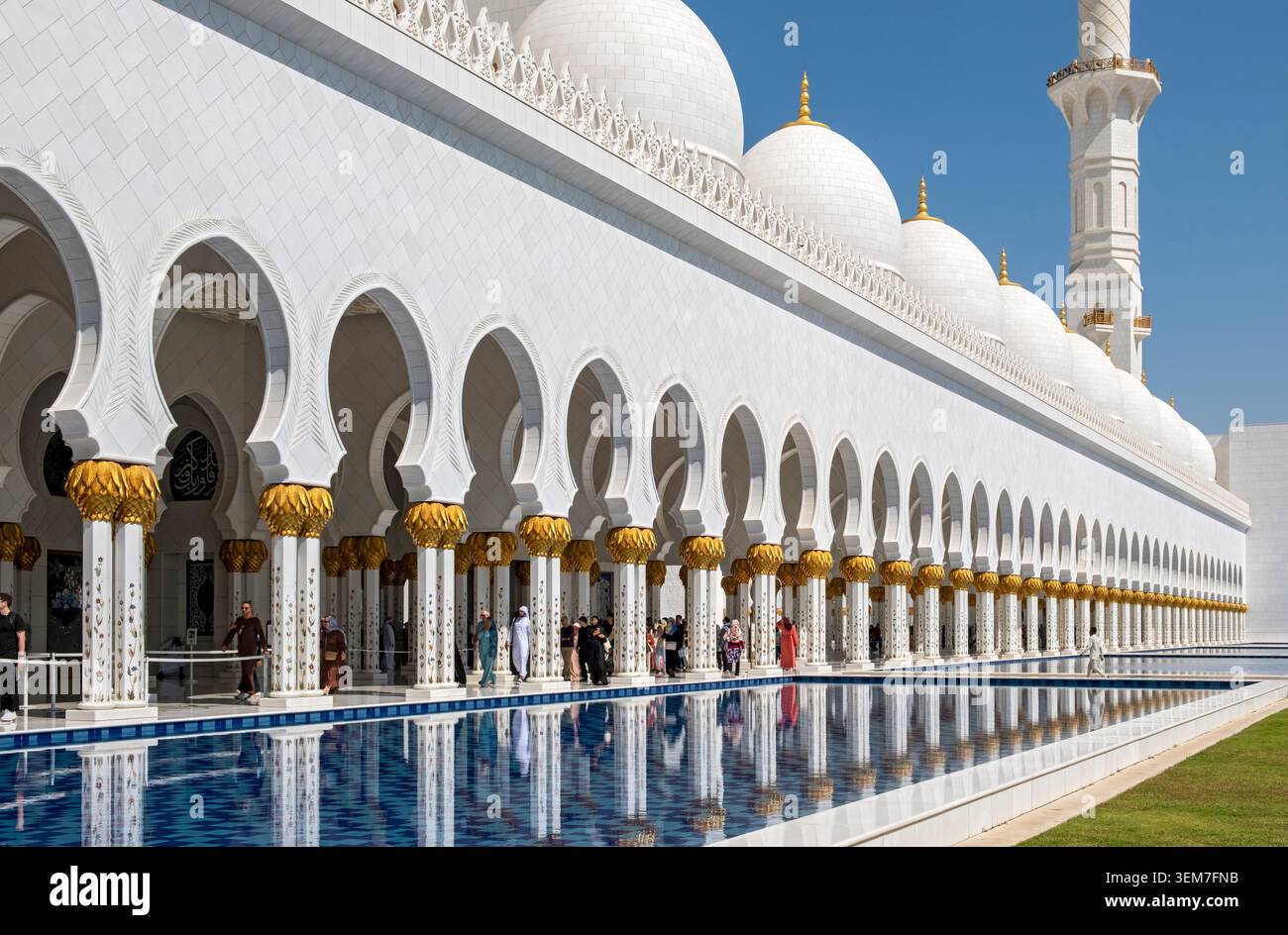 Portici in marmo bianco, cupole e piscina blu della grande Moschea dello Sceicco Zayed sotto un cielo limpido, Abu Dhabi, Emirati Arabi Uniti Foto Stock