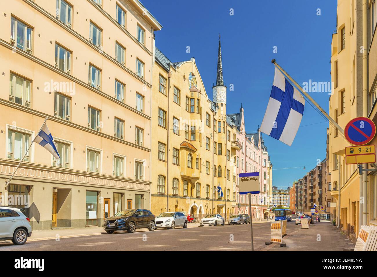 Una bella strada a Helsinki con colorati edifici storici con bandiere finlandesi sulle facciate, Finlandia Foto Stock