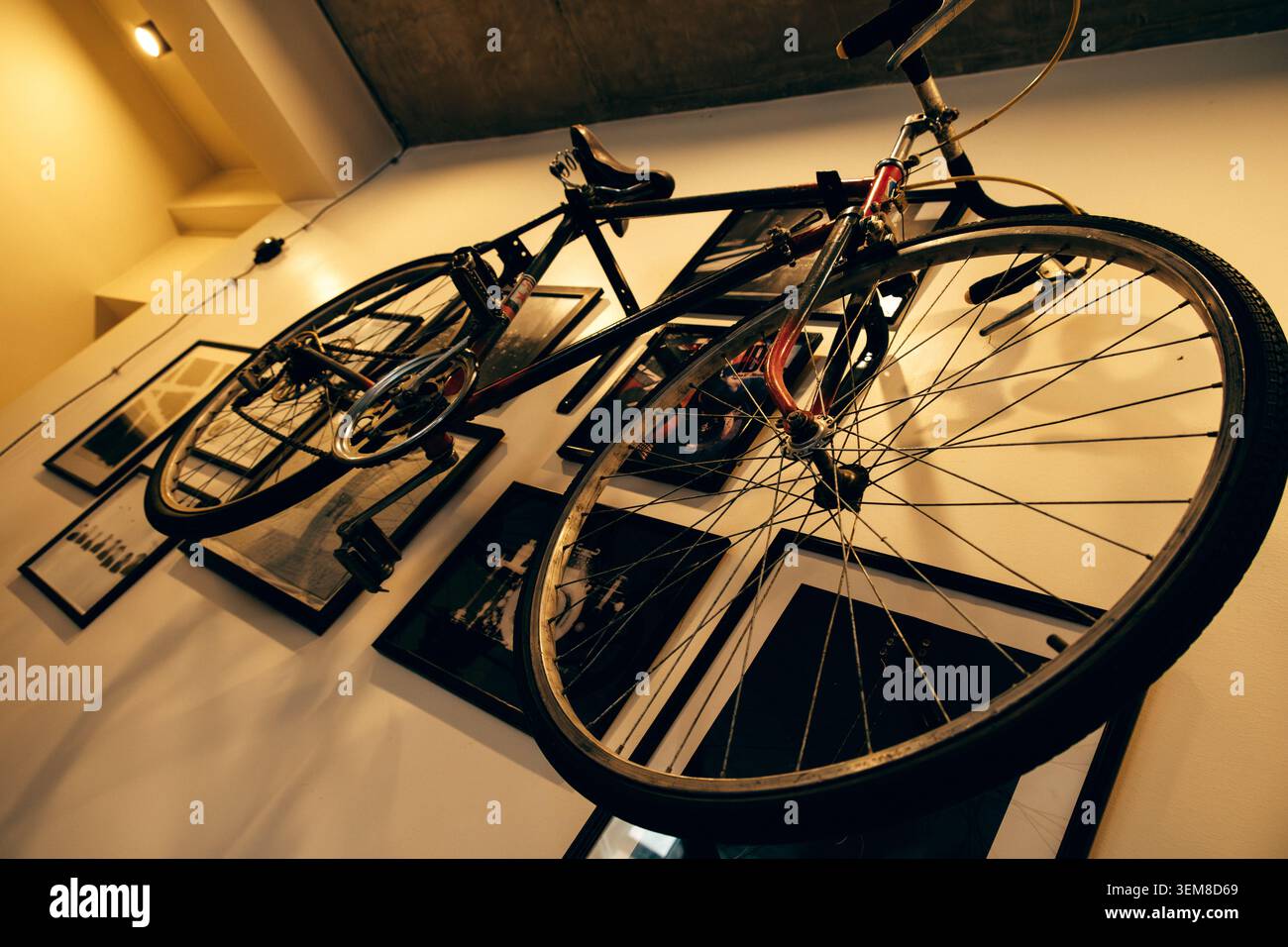 Bicicletta da strada d'epoca esposta come arte murale tra fotografie incorniciate e stampe grafiche in un interno elegante. Concetto creativo di arredamento per la casa che combina cy Foto Stock