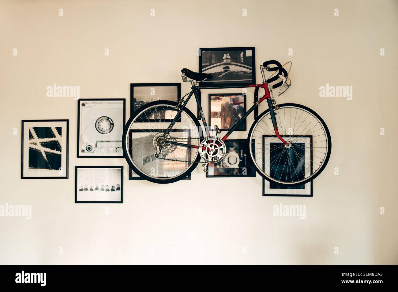 Bicicletta da strada d'epoca esposta come arte murale tra fotografie incorniciate e stampe grafiche in un interno elegante. Concetto creativo di arredamento per la casa che combina cy Foto Stock
