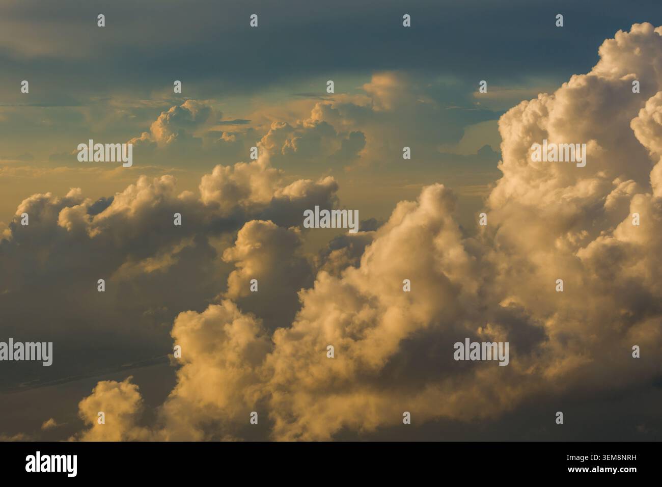 Le nuvole di cumulus thunderhead, illuminate da un'intensa luce solare dorata, proiettano profonde e spettacolari ombre nel cielo serale. Foto Stock