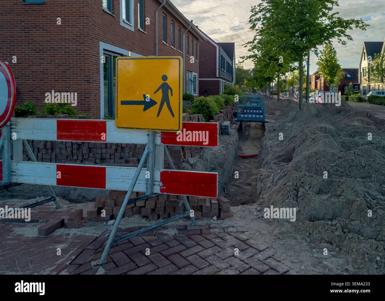 Barriera per cantieri edili e cartelli pedonali all'esterno delle moderne case in mattoni Foto Stock