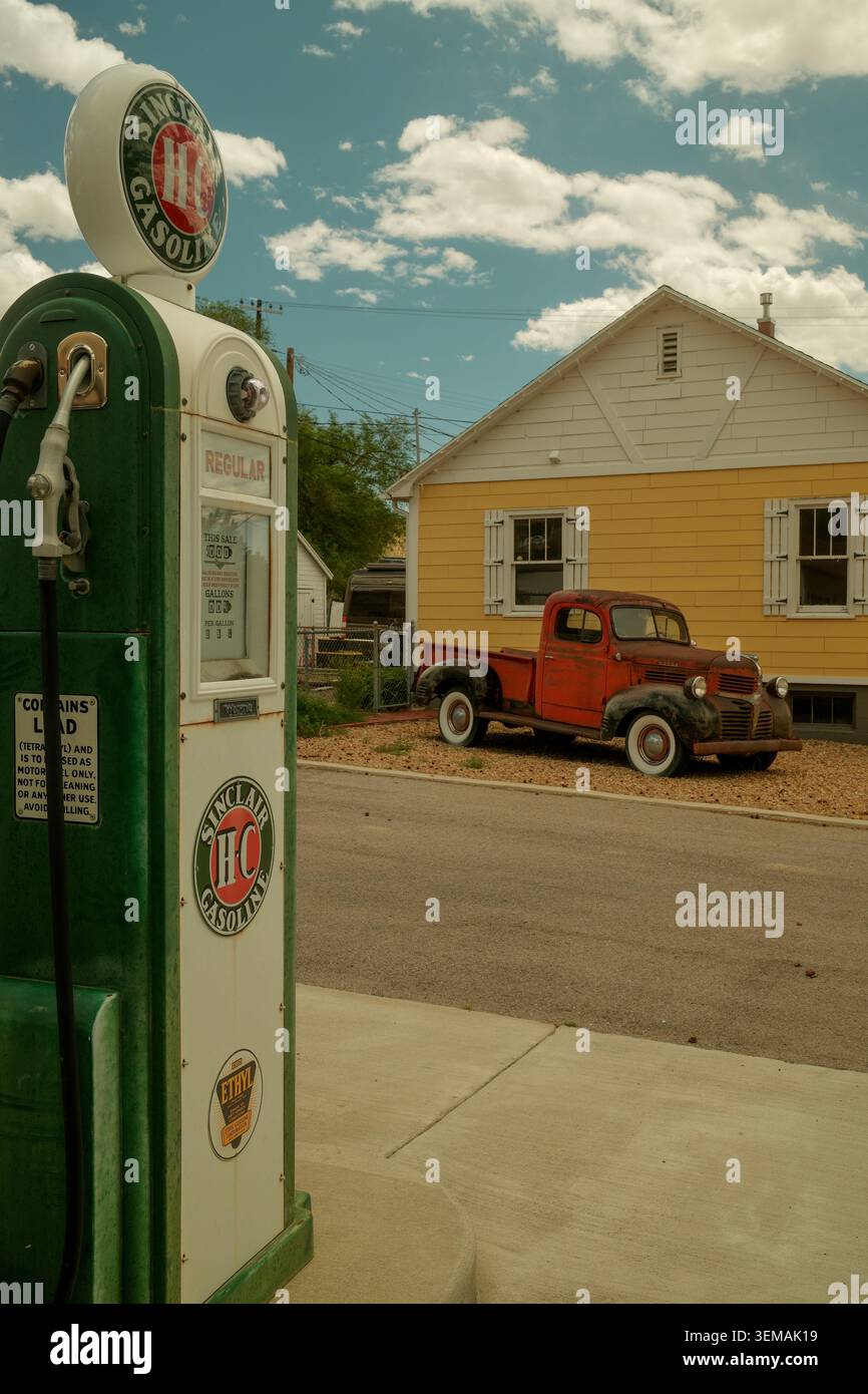 Pompa a benzina d'epoca restaurata di fronte a una storica casa gialla e a un camion rosso d'epoca ad Helper, Utah, Stati Uniti. Foto Stock