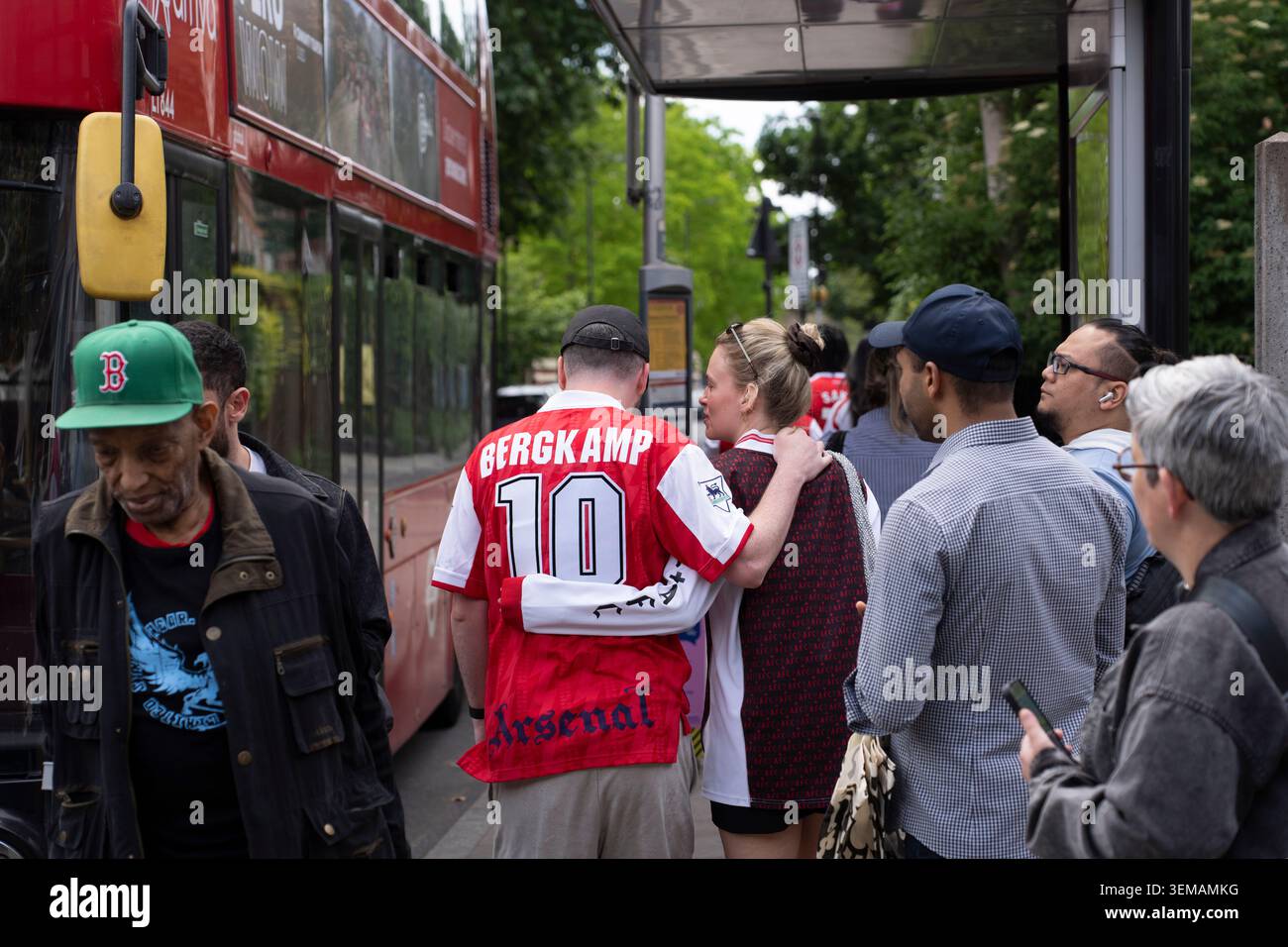 I tifosi delle maglie dell'Arsenal si riuniscono alla fermata dell'autobus di Londra, per anticipare una partita. Foto Stock