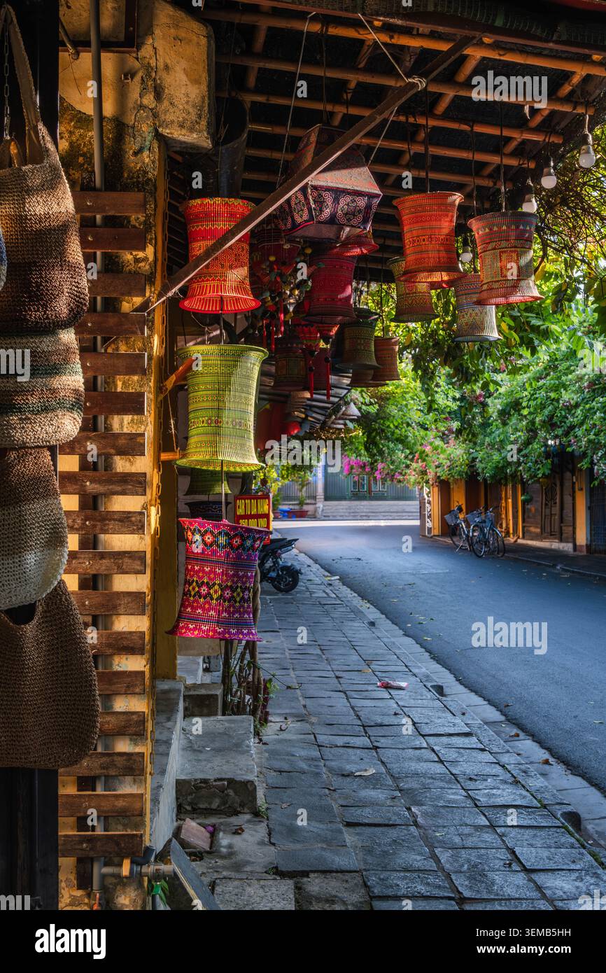 Borse in tessuto fatte a mano e lanterne colorate esposte lungo una tranquilla strada storica Foto Stock