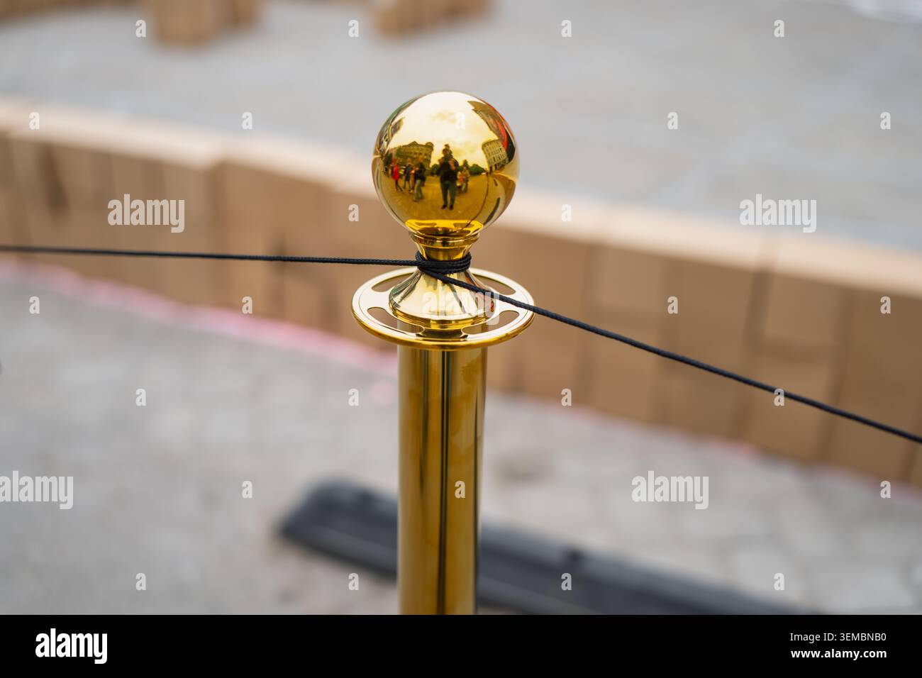 Montante di controllo Golden Crowd con parte superiore a sfera riflettente che regge una fune nera, infrastrutture di lusso per eventi e VIP Access Sector Foto Stock