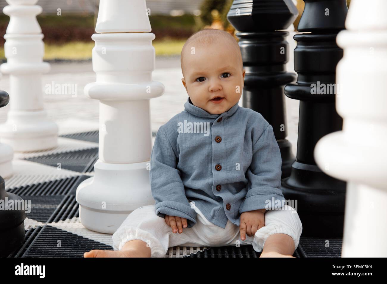 Simpatico baby sitter tra giganteschi pezzi di scacchi all'aperto concetto di apprendimento precoce e strategia Foto Stock