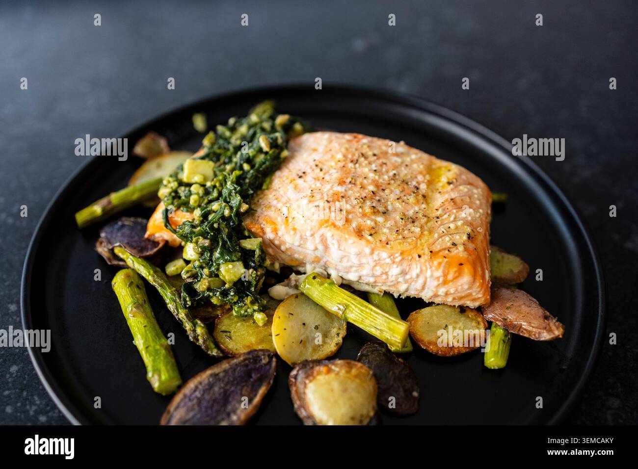 Salmone arrosto con basilico e pesto di semi di girasole. Patate arrosto e asparagi Foto Stock