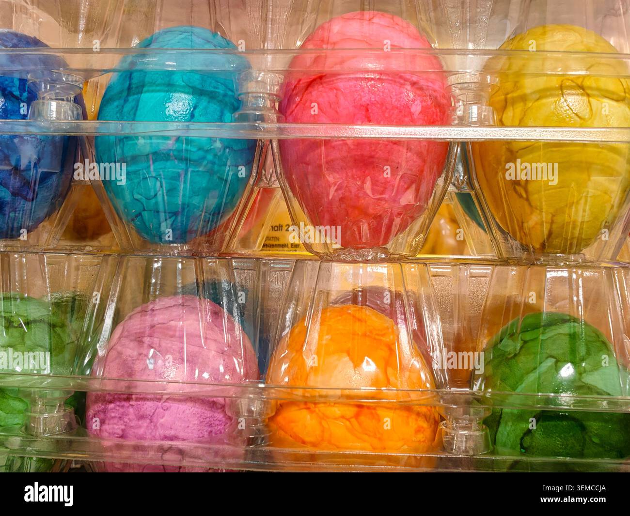 Una fila di brillanti palline da gelato in una vetrina in plastica trasparente, che mostra colori vivaci e texture cremose. L'illuminazione soffusa evidenzia una luce lucida Foto Stock