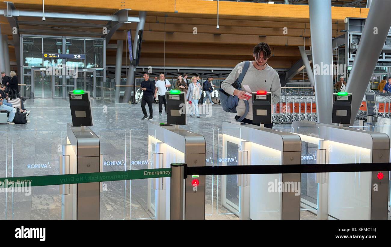 Un passeggero scansiona il suo biglietto ai cancelli di sicurezza automatizzati all'interno dell'aeroporto di Oslo gestiti da Avinor in Norvegia - Immagine stock catturata con smartphone