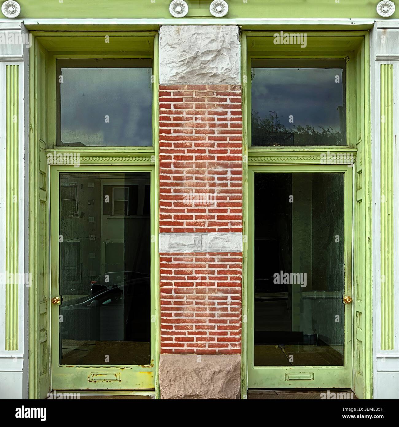 Ingresso incorniciato di verde che si apre all'interno di una facciata in mattoni rossi caratterizzata da grandi pannelli di vetro. Foto Stock
