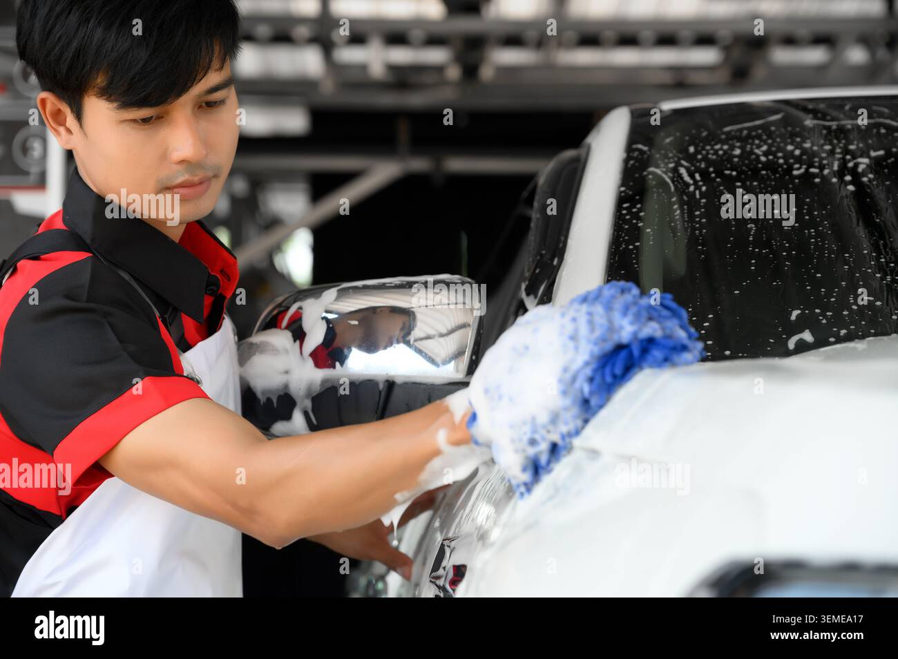 I lavoratori utilizzano il lavaggio con sapone e si prendono cura della carrozzeria del veicolo con diligenza, il lavaggio e i dettagli per veicoli lucidi e puliti per il settore automobilistico M. Foto Stock