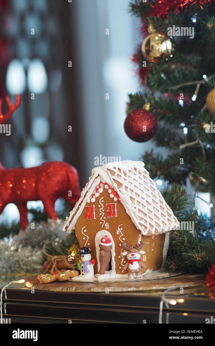 Decorazione della casa di pan di zenzero vicino a un albero di Natale Foto Stock