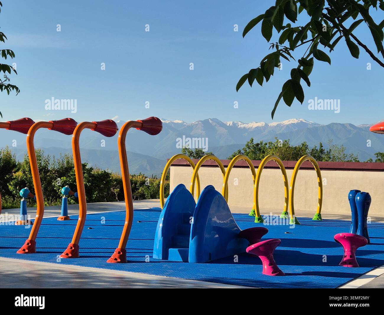 Parco giochi per bambini colorato e vuoto con montagne innevate del Caucaso. - Immagine stock catturata con smartphone