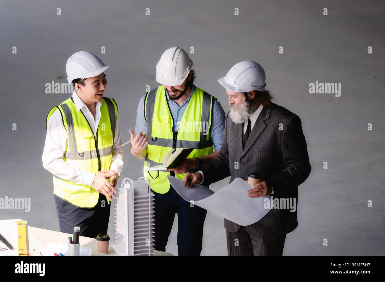 Gli sviluppatori immobiliari che esaminano il modello architettonico in spazi vuoti nel cantiere edile, godono di una vista ad angolo elevato per i responsabili del sito Foto Stock