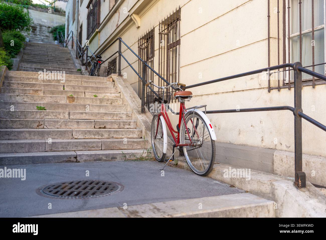 Budapest, Ungheria - 2 maggio 2026: Bicicletta appoggiata su gradini di pietra in una tranquilla strada residenziale di Budapest Foto Stock