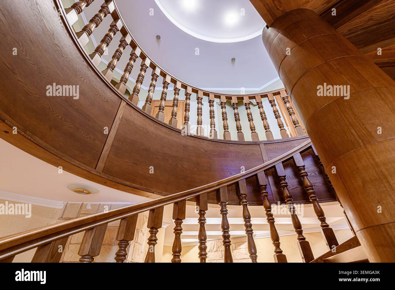 l'angolo basso presenta una scala a chiocciola realizzata in legno che si snoda verso l'alto verso il soffitto con illuminazione incassata, che mette in risalto l'intricato balaustra Foto Stock