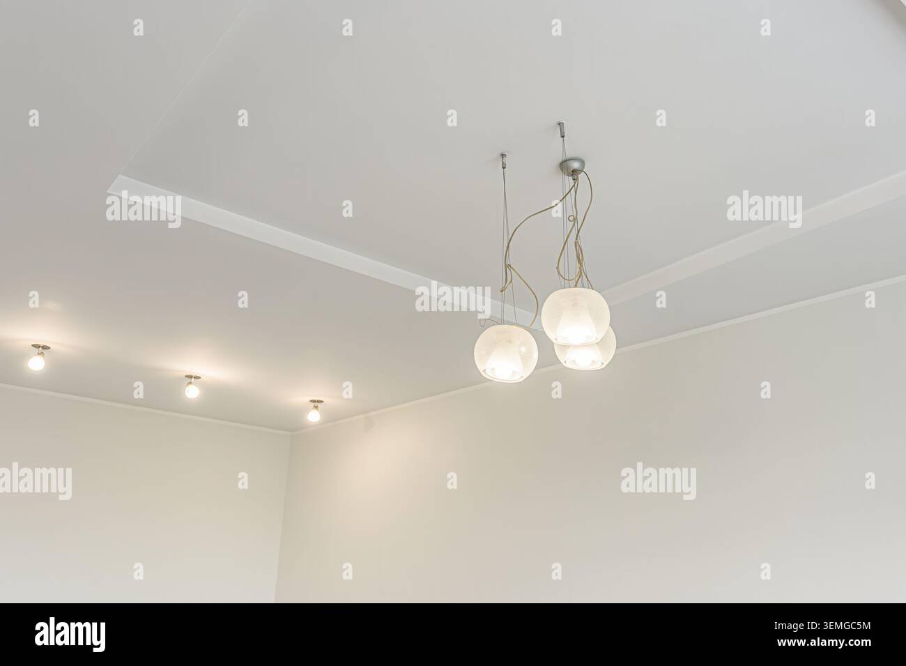 gli interni moderni presentano un soffitto bianco con luci da incasso e un gruppo di luci a sospensione a globo. Anche le pareti sono bianche, a creare una a minimalista Foto Stock
