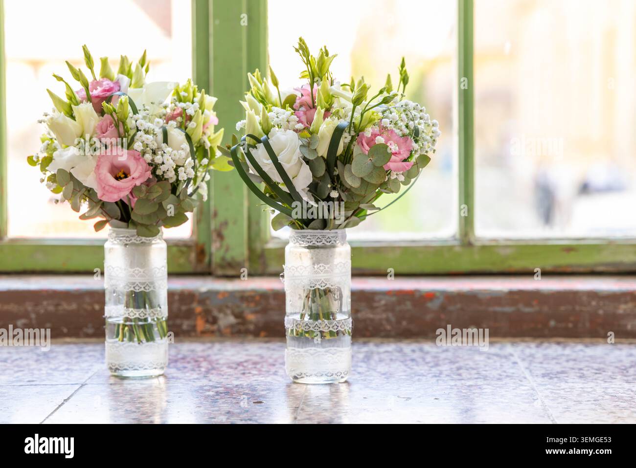 Mazzi di fiori per nozze con rose rosa e bianche in vasi di vetro decorati Foto Stock