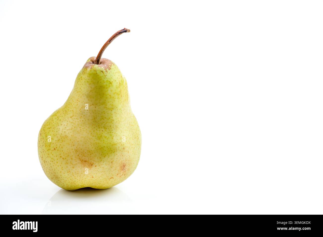 Una pera solitaria, fresca, giallo-verde con un delicato gambo marrone si staglia su uno sfondo bianco puro, evidenziando la sua forma e texture naturali Foto Stock