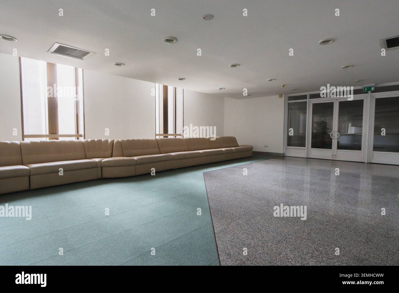 Le finestre luminose lasciano inondare la luce naturale dello spazio. Design pulito e moderno con arredi minimali. Ideale per riunioni o momenti di relax Foto Stock