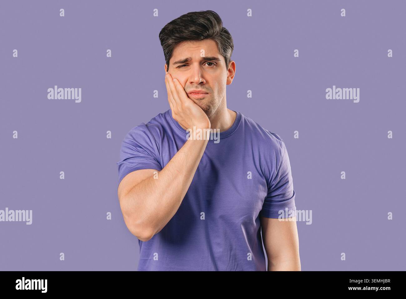 Uomo maturo che tocca la guancia con espressione dolorosa, reagendo a mal di denti improvvisi Foto Stock