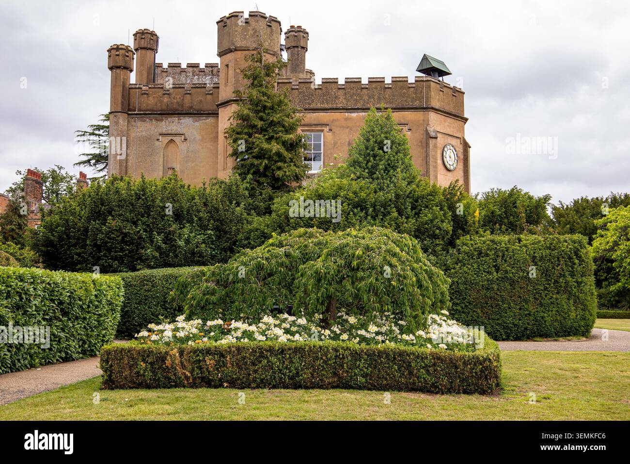 Casa padronale Nonsuch a Cheam nel Surrey in Inghilterra con giardini formali, un prato ben curato, sotto un cielo nuvoloso e un grande orologio frontale Foto Stock
