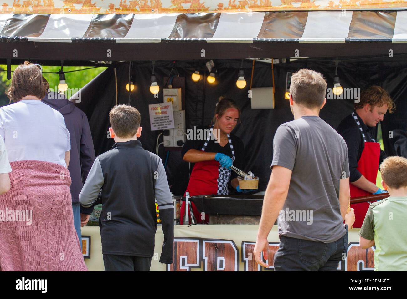I venditori di bancarelle servono cibo da strada caldo ai clienti in fila al Victoria Park durante il festival annuale del cibo e delle bevande di Southport. Foto Stock