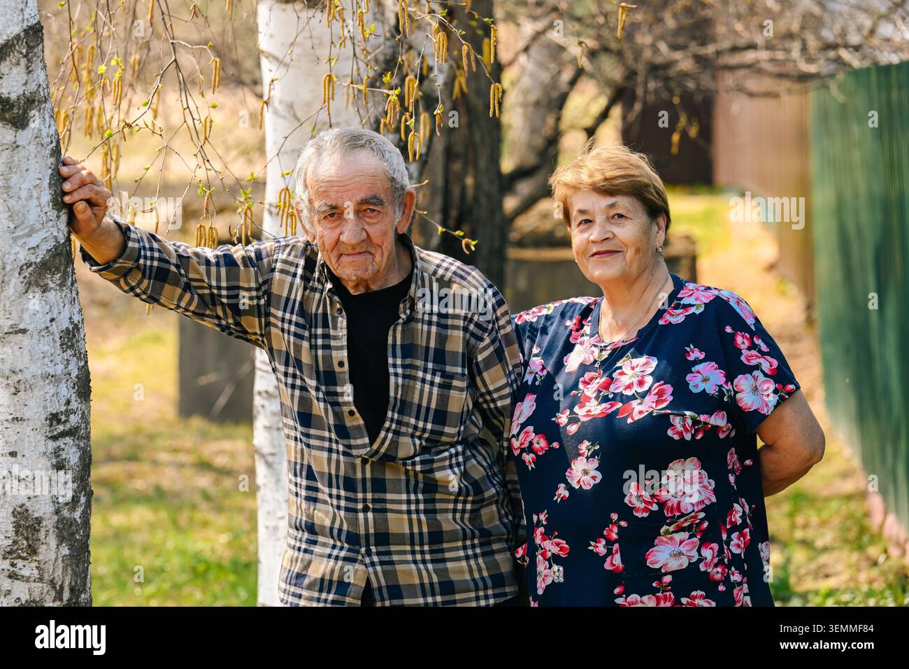 Ritratto della coppia russa anziana marito 77 anni e moglie 73 anni in piedi vicino all'albero di betulla nel giardino del villaggio rurale Foto Stock