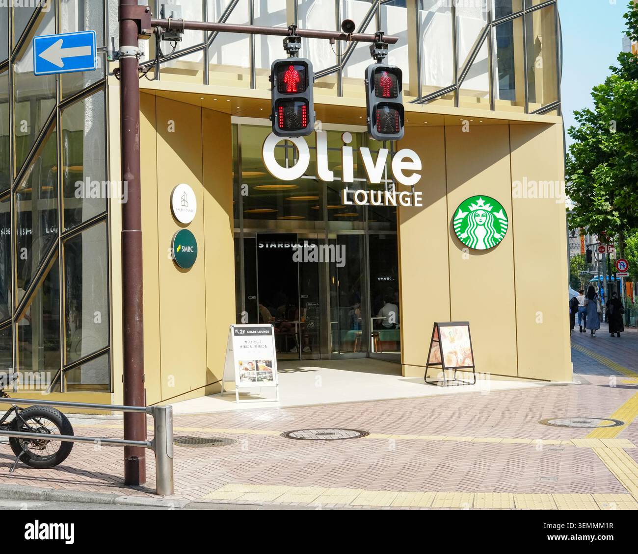 Tokyo, Giappone – 30 agosto 2025: Olive LOUNGE Shibuya e vetrina di Starbucks sotto i segnali pedonali. Foto Stock