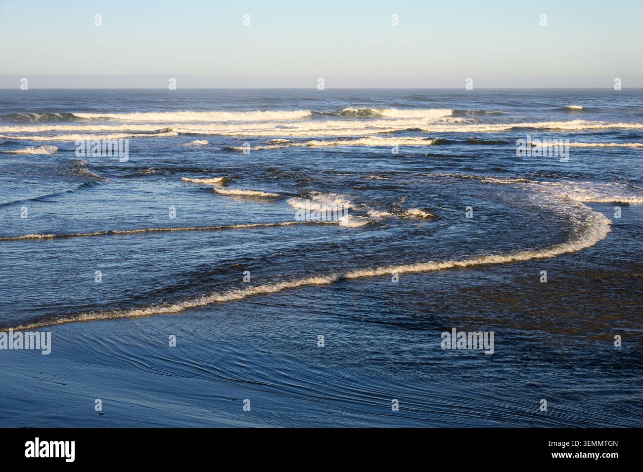 Le onde si infrangono in onde oceaniche che si infrangono in prossimità della spiaggia con orizzonte chiaro Foto Stock