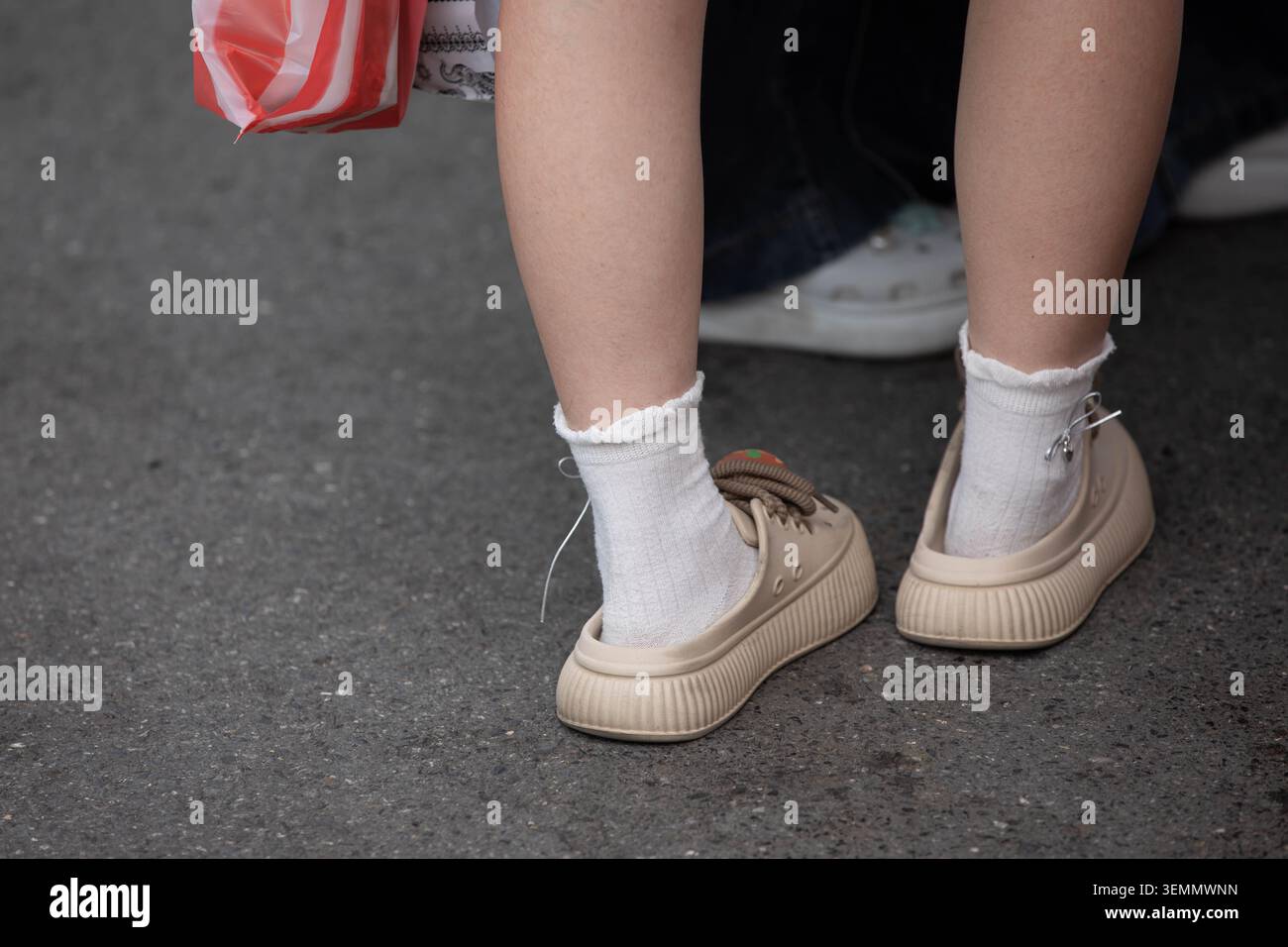 Donna in scarpe di gomma beige che cammina nel mercato, vista ad angolo alto Foto Stock