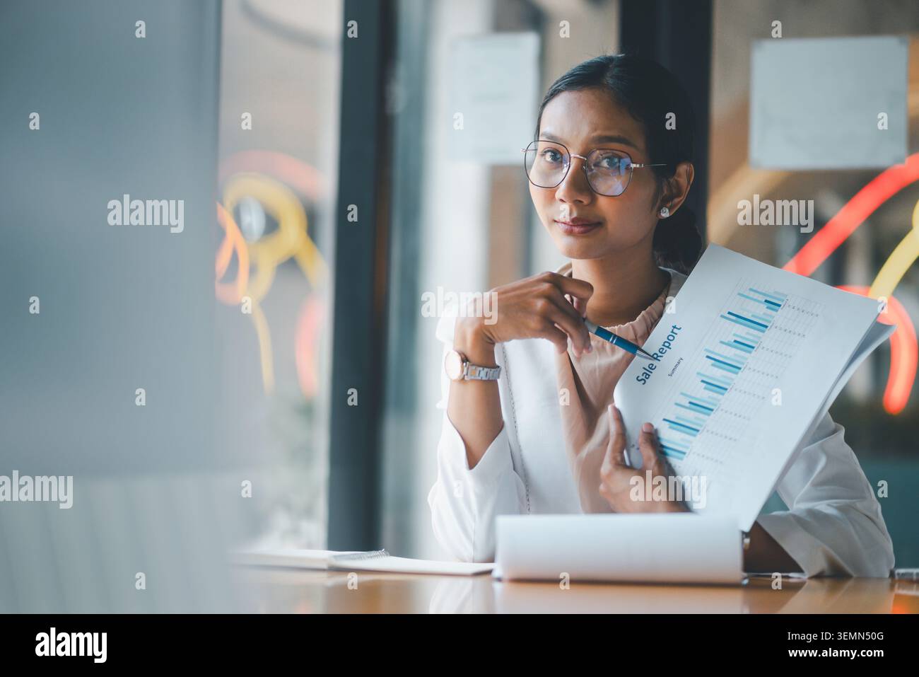 Donna d'affari con report sulle vendite e penna alla scrivania dell'ufficio, che esamina il riepilogo dei grafici, i risultati aziendali e i dati finanziari con calma, sicurezza e professionalità Foto Stock
