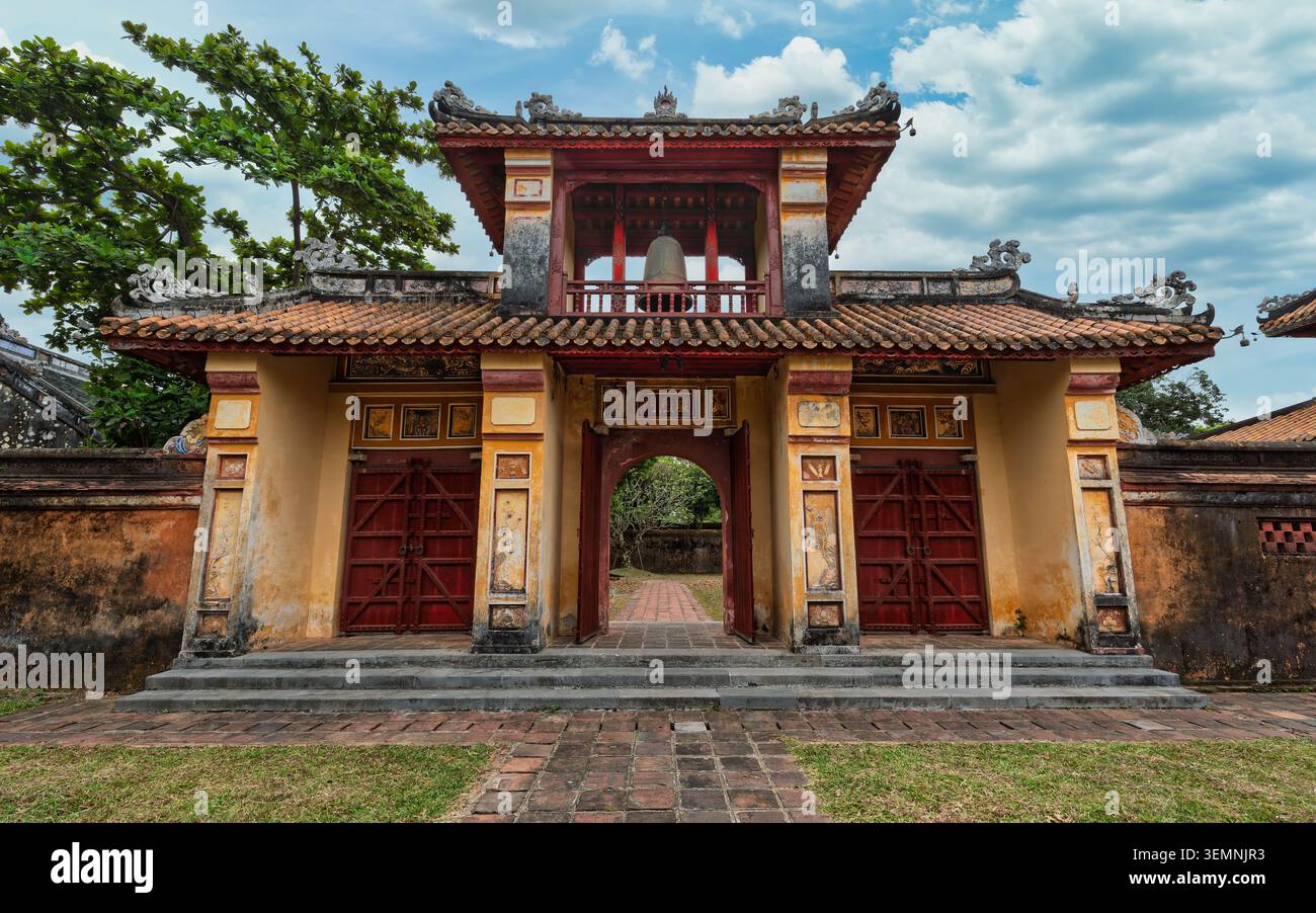 Storico cancello ornato che conduce al complesso del Tempio To a Hue, Vietnam. Tradizionale architettura vietnamita con tetto piastrellato di rosso, dettagli intricati, a. Foto Stock