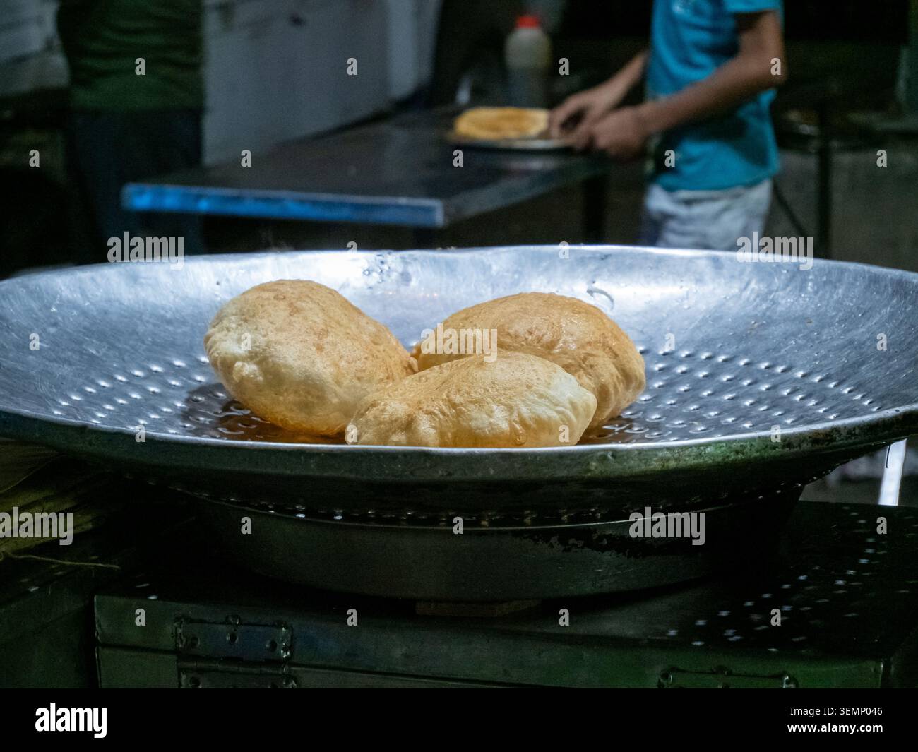 Il tradizionale pane puri indiano viene preparato sul momento su un vassoio in una vivace bancarella del mercato. Foto Stock