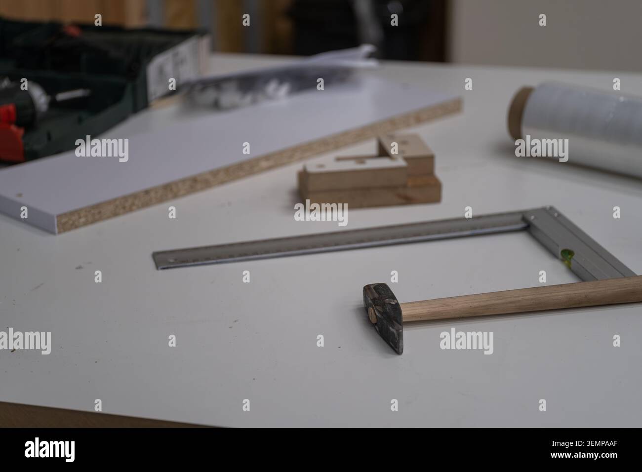 Piano di lavoro preparato per la produzione di mobili con strumenti di misurazione, accessori di assemblaggio, materiali di imballaggio e componenti di produzione. L'immagine r Foto Stock