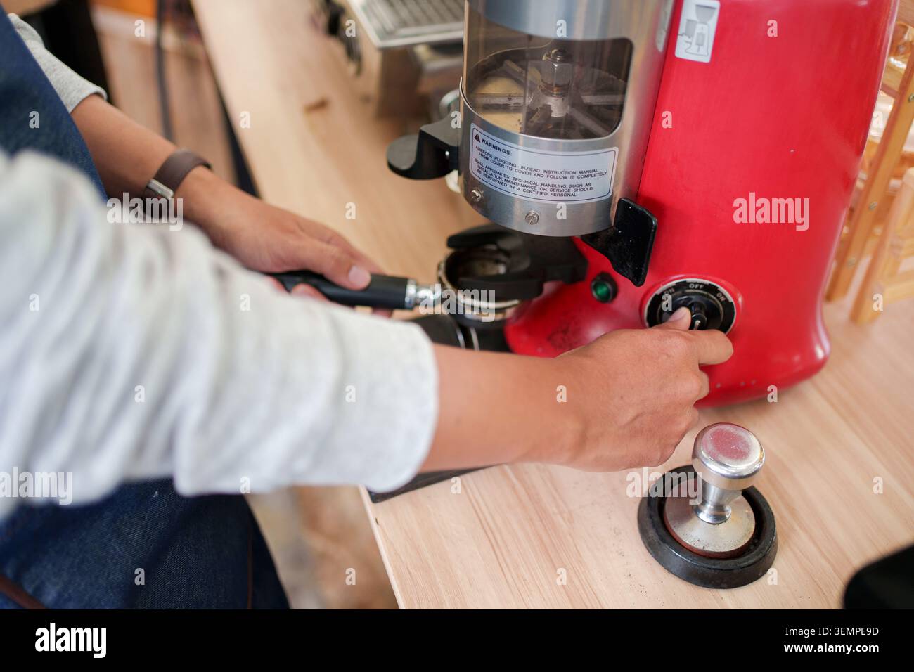 Il barista macina caffè fresco per un espresso Foto Stock