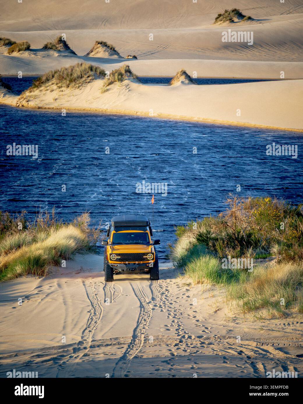 Veicolo fuoristrada giallo su un sentiero sabbioso dall'acqua Foto Stock