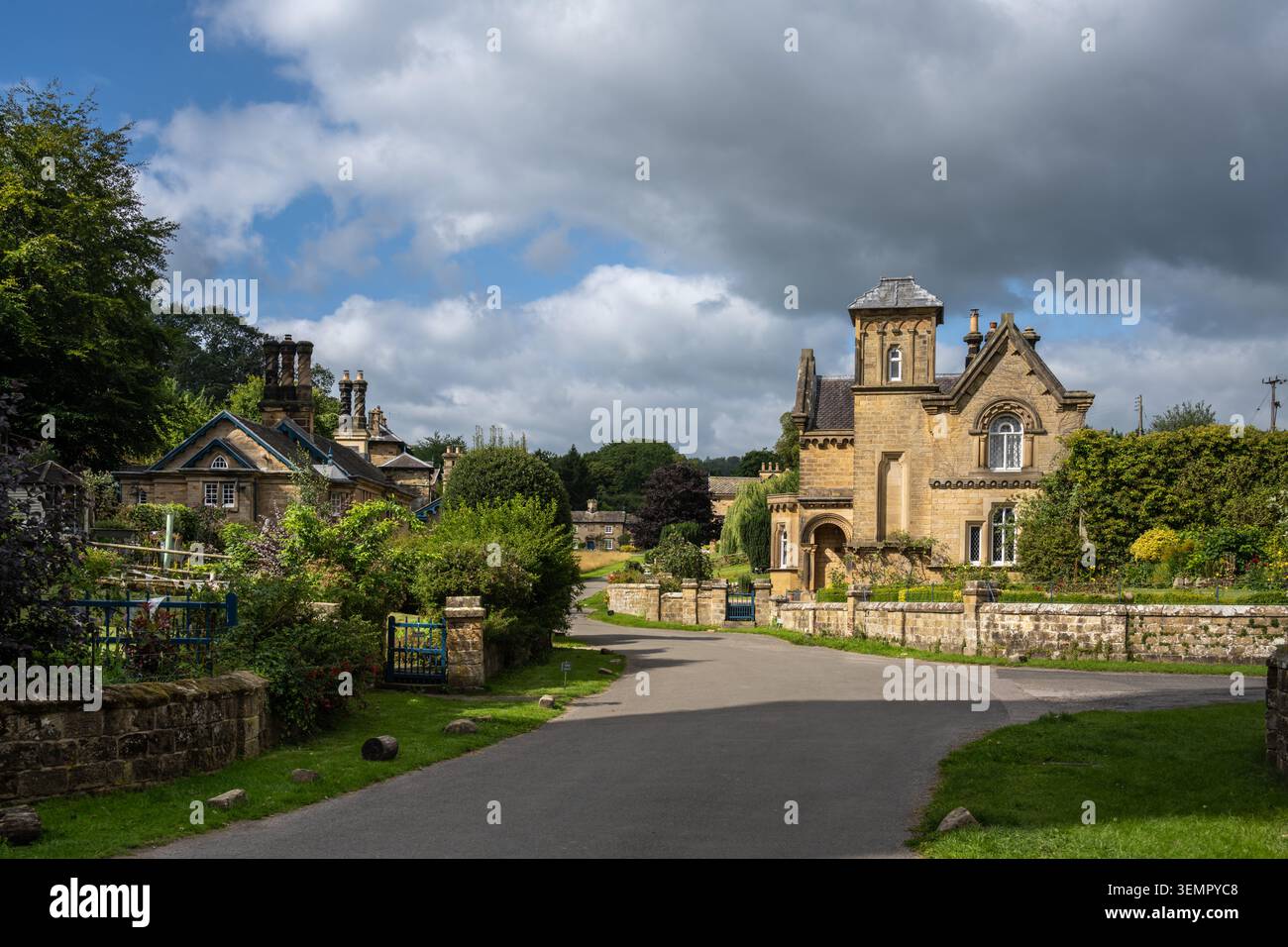 Una vista panoramica della strada catturata dove la corsia del villaggio si divide, mostrando eclettici cottage di pietra Foto Stock