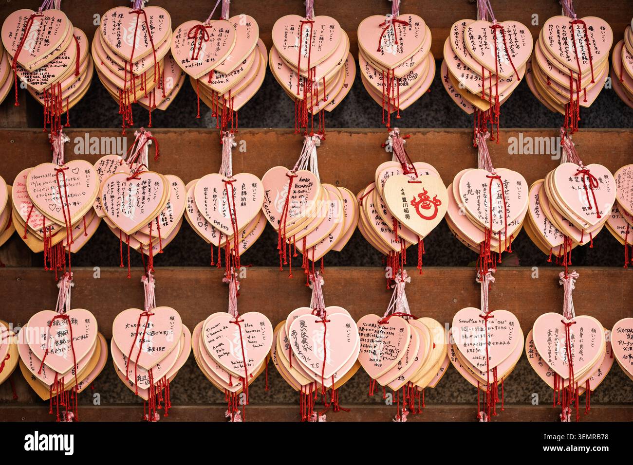 Disposizione a griglia di dozzine di placche di preghiera ema in legno a forma di cuore appese su una parete esposta in un santuario, Tokyo, Giappone Foto Stock