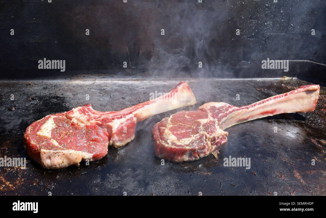 Bistecche di tomahawk fresche appena tostate su un barbecue piatto in metallo. Foto Stock