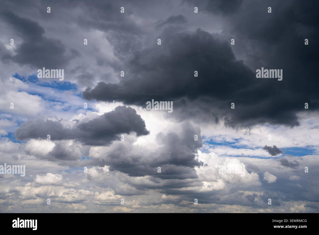 Un paesaggio nuvoloso spettacolare caratterizzato da nuvole di pioggia scure e macchie di luce dove la luce del sole si diffonde in una giornata mutevole. Uno sfondo meteorologico Foto Stock