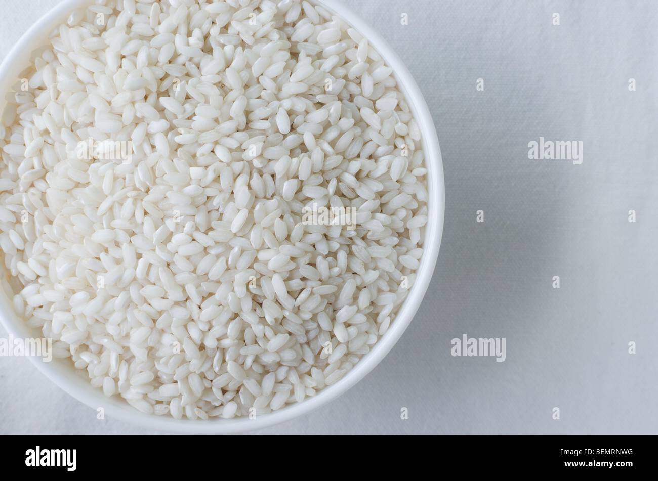 Una ciotola bianca di riso Arborio su sfondo bianco. Concetto di cucina italiana, risotto e alimentazione sana. Riso crudo. Cucina mediterranea. Foto Stock