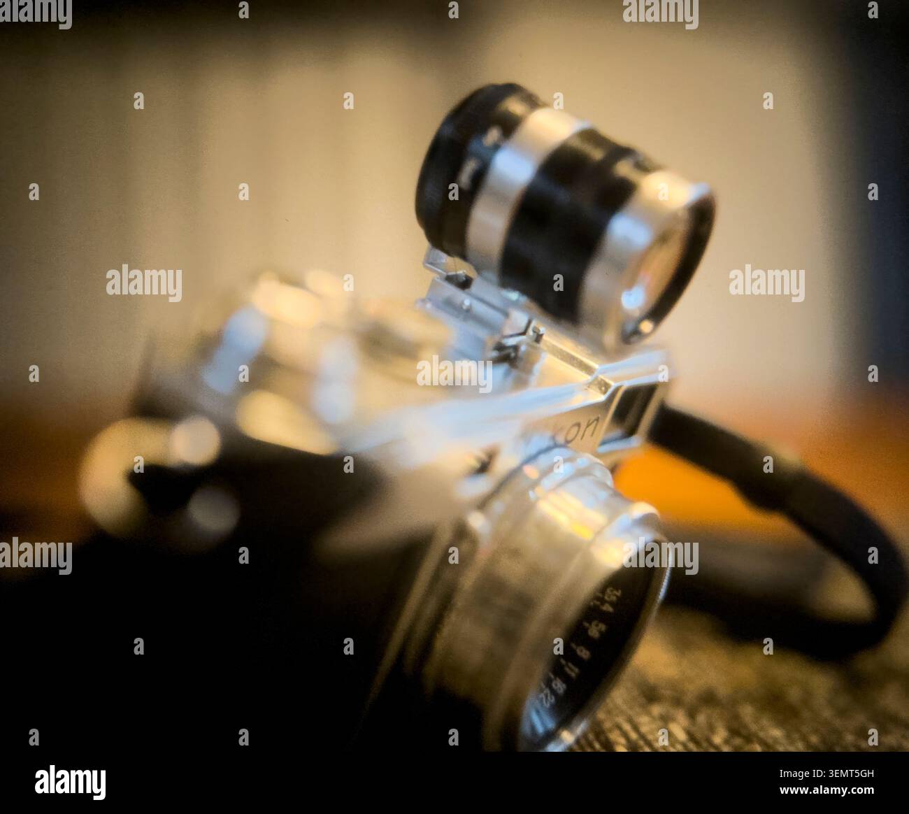 Una scintillante fotocamera Nikon analogica con telemetro a pellicola 1962 con un raro accessorio per mirino ottico montato sul pattino è illuminata da un'incredibile luce bokeh. Foto Stock