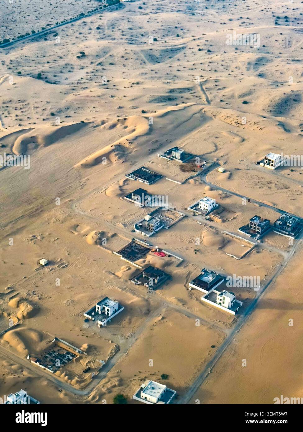 I complessi residenziali isolati e le abitazioni sparse punteggiano il remoto paesaggio desertico arido ai margini esterni di Dubai, Emirati Arabi Uniti. Foto Stock
