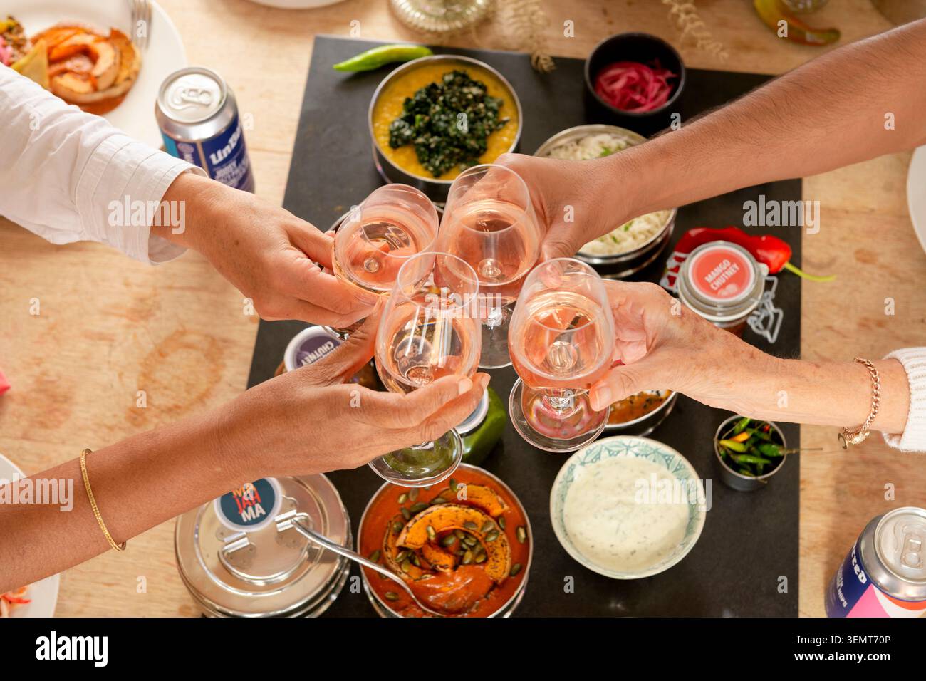 Celebra la cucina indiana con gli amici con piatti saporiti e bevande frizzanti Foto Stock