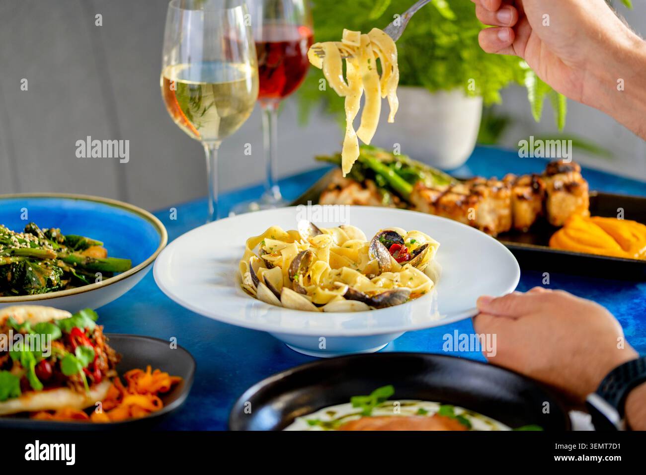 Delizioso piatto di pasta servito insieme a bevande vivaci e piatti colorati Foto Stock
