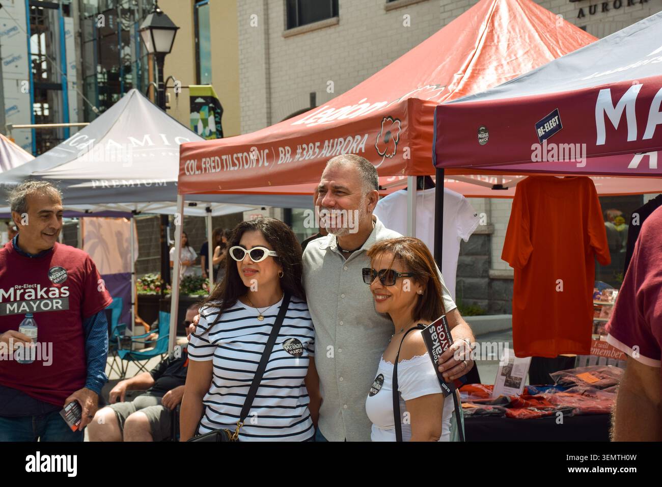 Aurora, Ontario, Canada - 7 giugno 2026: Il sindaco di Aurora Tom Mrakas posa per una fotografia con due donne all'Aurora Street Festival durante un municipio Foto Stock