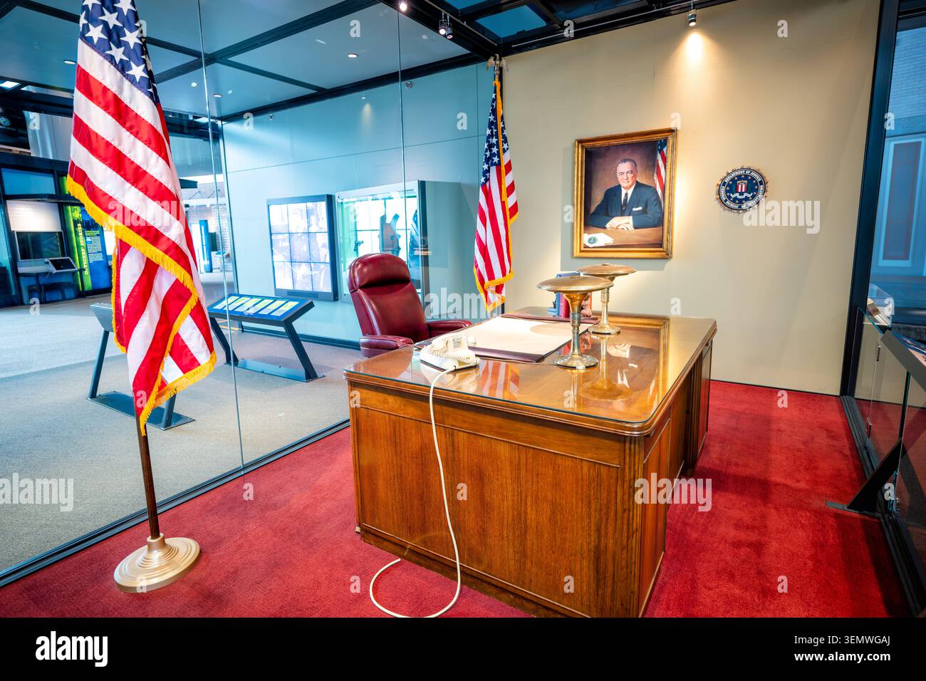 Recreazione dell'ufficio di J Edgar Hoover Museo Nazionale dell'Ordine Pubblico Washington DC | WASHINGTON D.C., Stati Uniti — Una ricreazione dell'ufficio di J. Edgar Hoover, ancorata dalla sua scrivania originale e dal ritratto a olio, si trova dietro il vetro al Museo Nazionale dell'Ordine Pubblico a Judiciary Square. Hoover ha guidato l'FBI dal 1924 al 1972, sedendosi a questa scrivania per quasi cinque decenni mentre trasformava l'ufficio in una potente agenzia di lotta al crimine e di intelligence. Il suo lascito rimane contestato per il programma COINTELPRO, che mirava ai leader dei diritti civili e ai dissidenti politici. Foto Stock